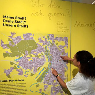 Ausstellungs-Besucherin vor dem Wandplan der Stadt Halle